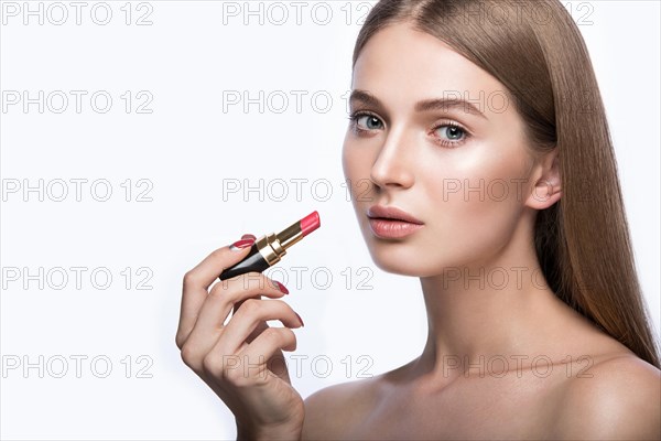 Beautiful young girl with a light natural make-up and beauty tools in hand. Picture taken in the studio on a white background