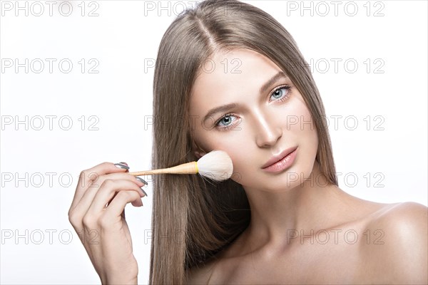 Beautiful young girl with a light natural make-up and beauty tools in hand. Picture taken in the studio on a white background