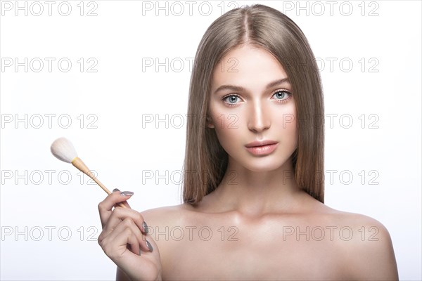 Beautiful young girl with a light natural make-up and beauty tools in hand. Picture taken in the studio on a white background