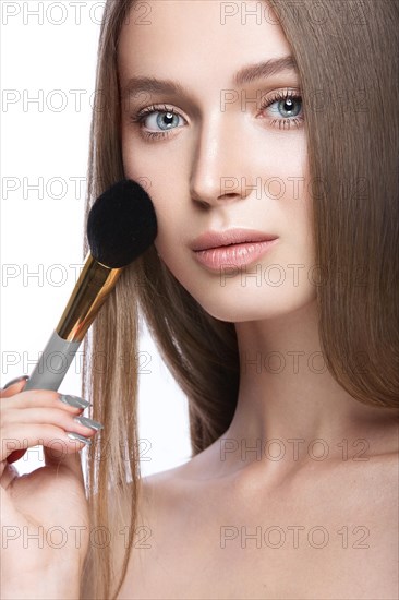 Beautiful young girl with a light natural make-up and beauty tools in hand. Picture taken in the studio on a white background