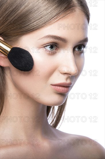 Beautiful young girl with a light natural make-up and beauty tools in hand. Picture taken in the studio on a white background