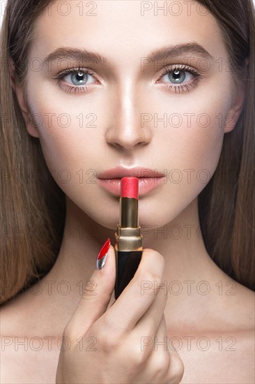 Beautiful young girl with a light natural make-up and beauty tools in hand. Picture taken in the studio on a white background