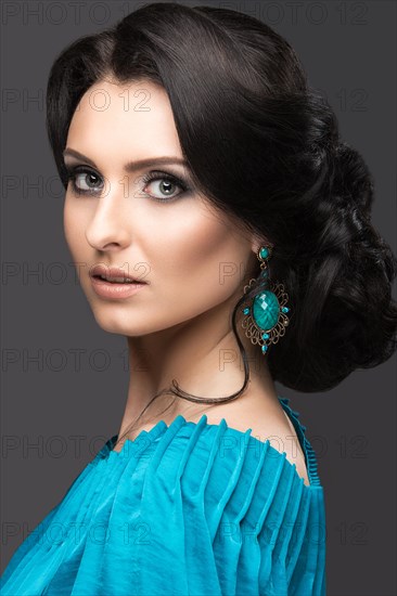 Beautiful girl in a blue dress with evening make-up and hairstyle. Beauty face. Picture taken in the studio on a black background. Hairstyle back view