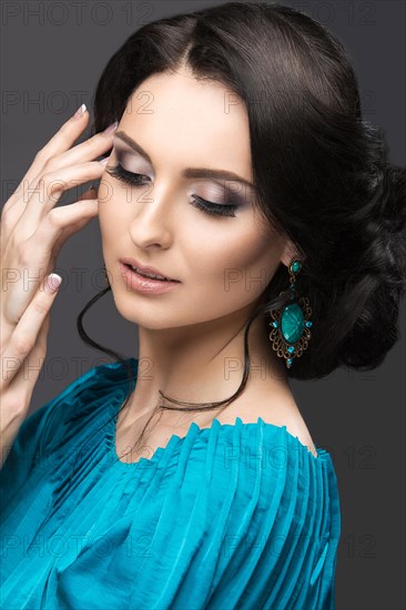 Beautiful girl in a blue dress with evening make-up and hairstyle. Beauty face. Picture taken in the studio on a black background. Hairstyle back view