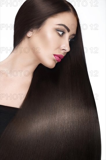 Beautiful brunette girl with a perfectly smooth hair and classic make-up. Beauty face. Picture taken in the studio on a white background