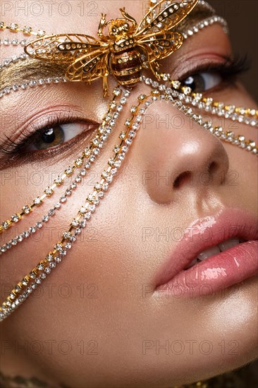 Beautiful girl in a golden mask and bright evening make-up. Beauty face. Photo taken in studio