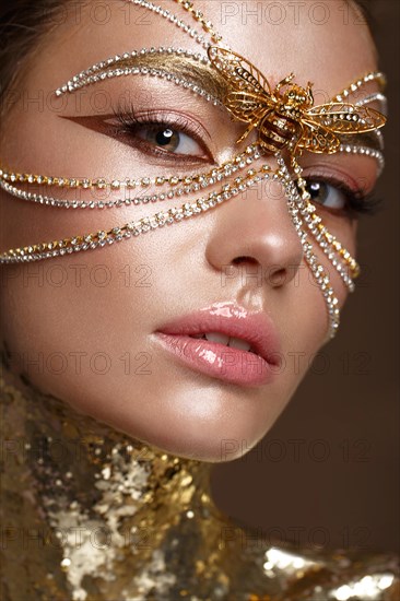 Beautiful girl in a golden mask and bright evening make-up. Beauty face. Photo taken in studio