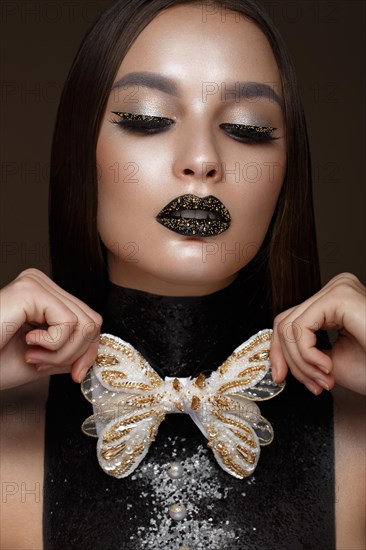 Beautiful girl with black creative art make-up and gold accessories. Beauty face. Photos shot in studio