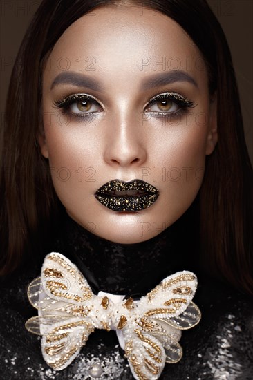 Beautiful girl with black creative art make-up and gold accessories. Beauty face. Photos shot in studio