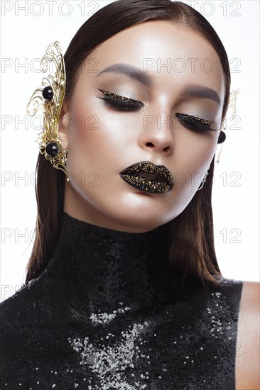 Beautiful girl with black creative art make-up and gold accessories. Beauty face. Photos shot in studio