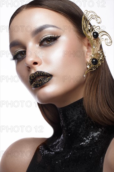 Beautiful girl with black creative art make-up and gold accessories. Beauty face. Photos shot in studio