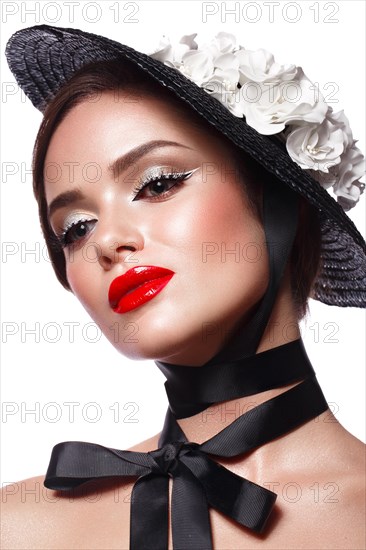Beautiful girl in a black hat with flowers and retro makeup. Beauty face. Photo taken in the studio