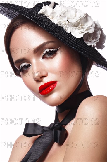 Beautiful girl in a black hat with flowers and retro makeup. Beauty face. Photo taken in the studio