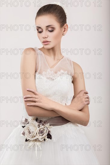 Portrait of a beautiful blond girl in image of the bride with purple flowers on her head. Beauty face. Photo shot in the Studio on a grey background