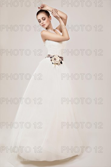 Portrait of a beautiful blond girl in image of the bride with purple flowers on her head. Beauty face. Photo shot in the Studio on a grey background