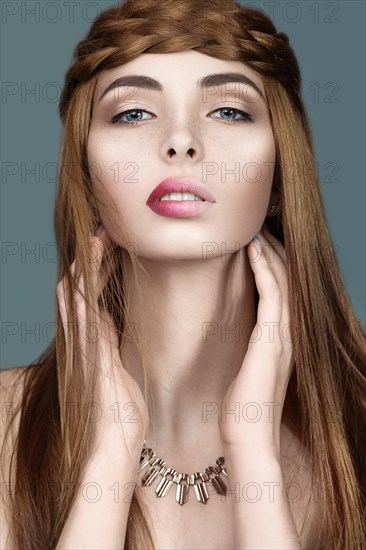 Beautiful red-haired girl with a pigtail hair and unusual lips. Portrait shot in the studio on a blue background