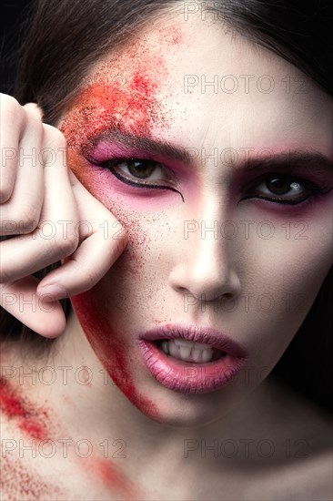 Portrait of a beautiful Girl with red paint on her face. Art beauty image. Photo shot in the Studio on a black background