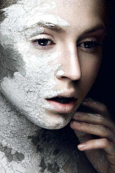 Beautiful girl with mud on his face. Cosmetic mask. Beauty face. Picture taken in the studio on a black background