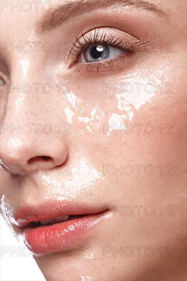 Beautiful young girl with a light natural make-up and perfect wet skin. Beauty face. Picture taken in the studio on a white background