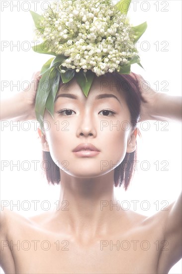 Fashion beautiful girl oriental type with delicate natural make-up and flowers. Beauty face. Picture taken in the studio on a white background