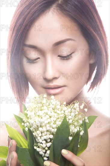 Fashion beautiful girl oriental type with delicate natural make-up and flowers. Beauty face. Picture taken in the studio on a white background