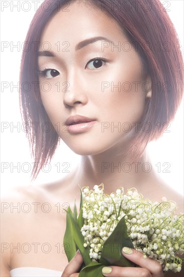 Fashion beautiful girl oriental type with delicate natural make-up and flowers. Beauty face. Picture taken in the studio on a white background