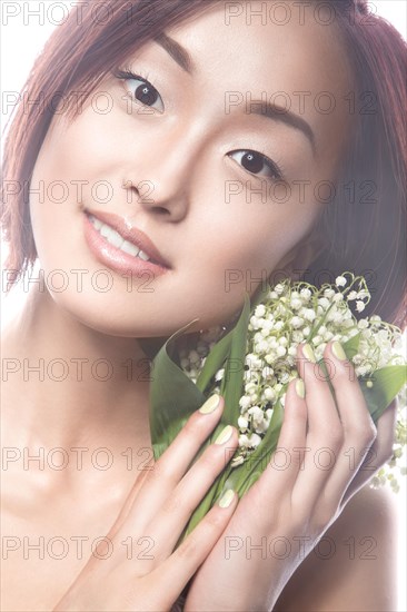 Fashion beautiful girl oriental type with delicate natural make-up and flowers. Beauty face. Picture taken in the studio on a white background