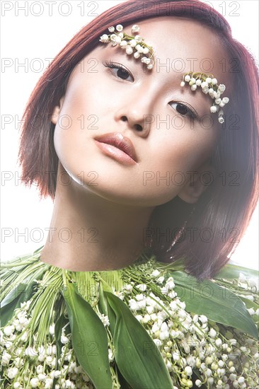 Fashion beautiful girl oriental type with delicate natural make-up and flowers. Beauty face. Picture taken in the studio on a white background