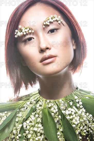 Fashion beautiful girl oriental type with delicate natural make-up and flowers. Beauty face. Picture taken in the studio on a white background