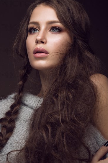 Beautiful young girl with gentle make-up in warm sweater and long straight hair. Beauty face. Studio portrait