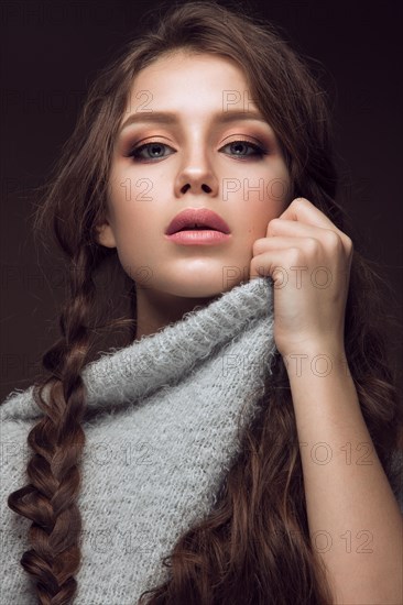 Beautiful young girl with gentle make-up in warm sweater and long straight hair. Beauty face. Studio portrait