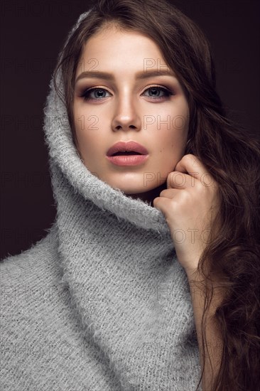 Beautiful young girl with gentle make-up in warm sweater and long straight hair. Beauty face. Studio portrait