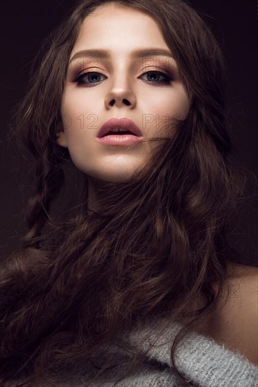 Beautiful young girl with gentle make-up in warm sweater and long straight hair. Beauty face. Studio portrait