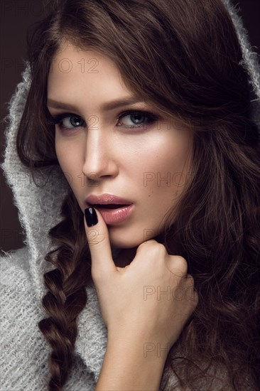 Beautiful young girl with gentle make-up in warm sweater and long straight hair. Beauty face. Studio portrait