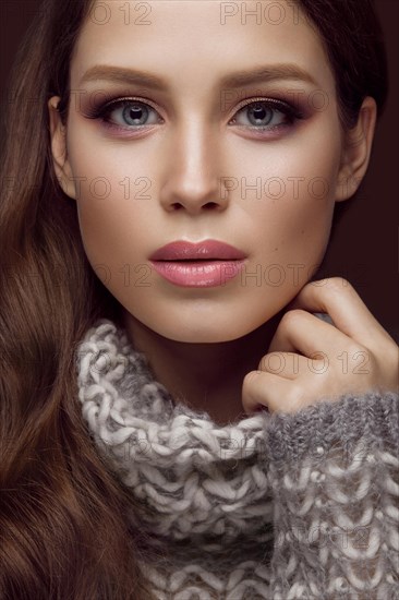 Beautiful young girl with gentle make-up in warm sweater and long straight hair. Beauty face. Studio portrait