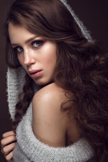 Beautiful young girl with gentle make-up in warm sweater and long straight hair. Beauty face. Studio portrait