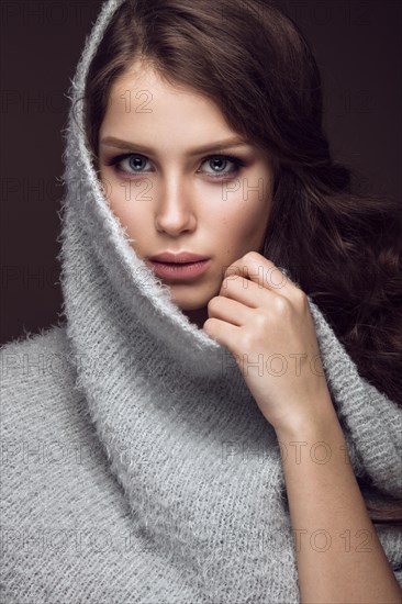 Beautiful young girl with gentle make-up in warm sweater and long straight hair. Beauty face. Studio portrait