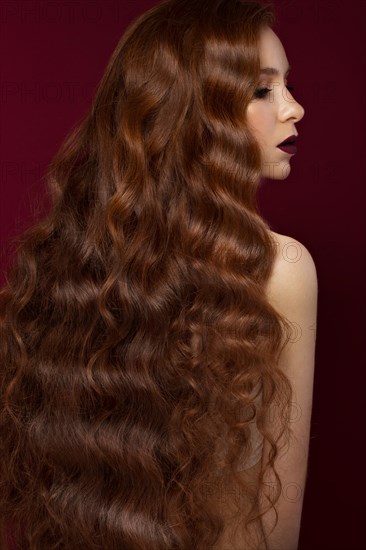 Beautiful Redhead girl with a perfectly curls hair and classic make-up. Beauty face. Picture taken in the studio