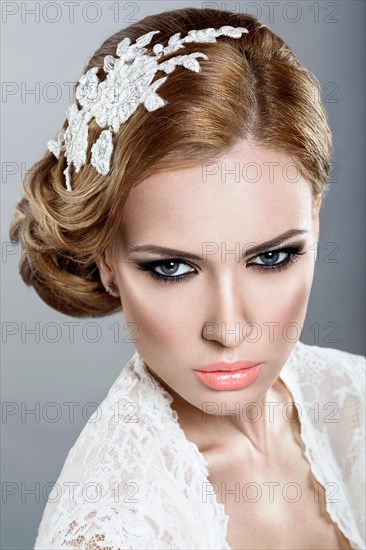 Portrait of a beautiful blonde woman in the image of the bride with flowers in her hair. Picture taken in the studio on a blue background