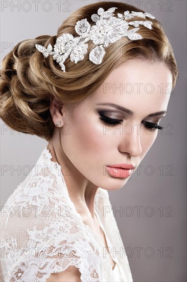 Portrait of a beautiful blonde woman in the image of the bride with flowers in her hair. Picture taken in the studio on a blue background