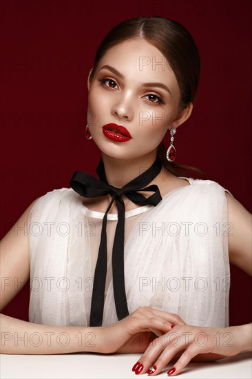 Beautiful girl in white dress with classic make-up and red manicure. Beauty face. Photo taken in the studio