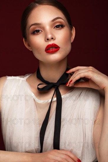 Beautiful girl in white dress with classic make-up and red manicure. Beauty face. Photo taken in the studio