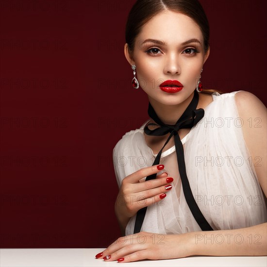 Beautiful girl in white dress with classic make-up and red manicure. Beauty face. Photo taken in the studio