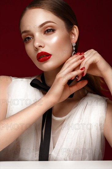 Beautiful girl in white dress with classic make-up and red manicure. Beauty face. Photo taken in the studio