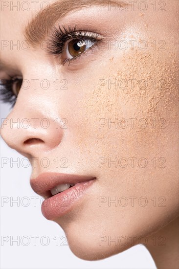 Beautiful young girl with tone powder on the skin. Beauty face. Picture taken in the studio on a white background