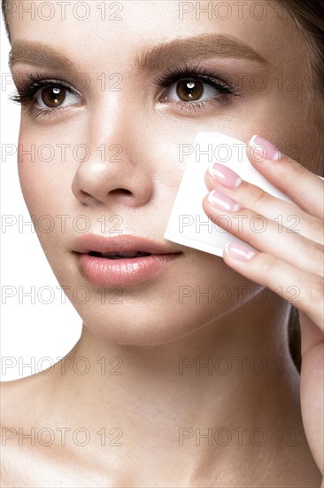 Beautiful young girl with wipes for removing makeup and French manicure. Beauty face. Picture taken in the studio on a white background