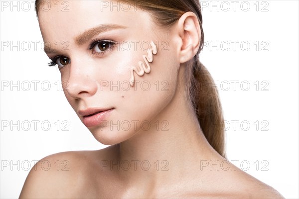 Beautiful young girl with tone cream on her skin. Beauty face. Picture taken in the studio on a white background