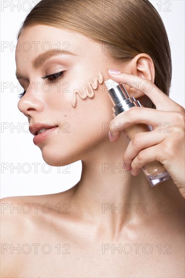 Beautiful young girl with tone cream on her skin. Beauty face. Picture taken in the studio on a white background