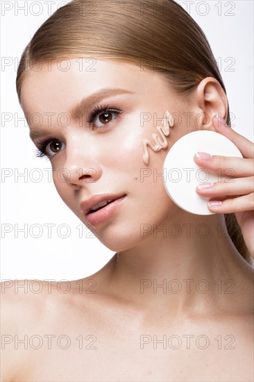 Beautiful young girl with sponge for application make-up and French manicure. Beauty face. Picture taken in the studio on a white background