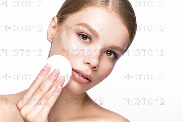 Beautiful young girl with sponge for application make-up and French manicure. Beauty face. Picture taken in the studio on a white background